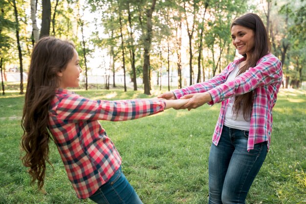 Madre e hija sonrientes que juegan en parque