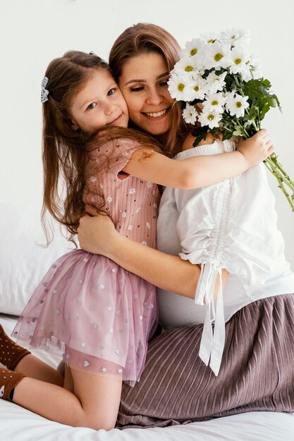 Madre e hija sonrientes con ramo de flores de primavera