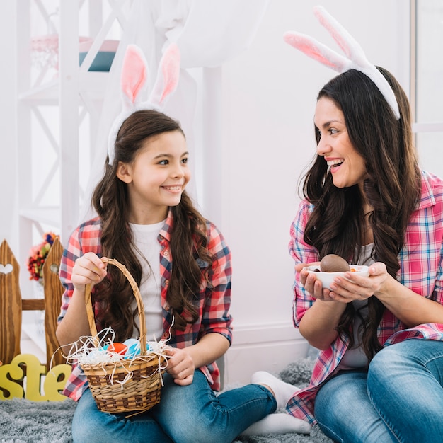 Madre e hija sosteniendo huevos de Pascua en la mano mirando el uno al otro