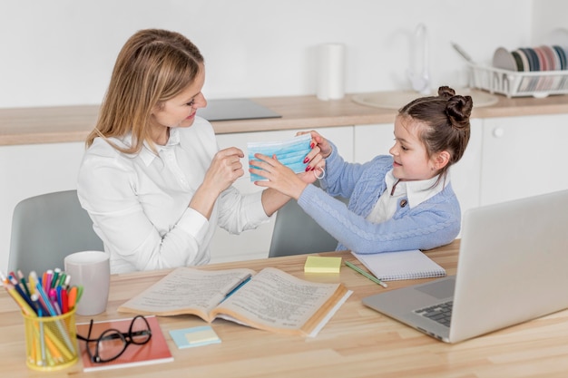 Madre e hija sosteniendo una máscara médica