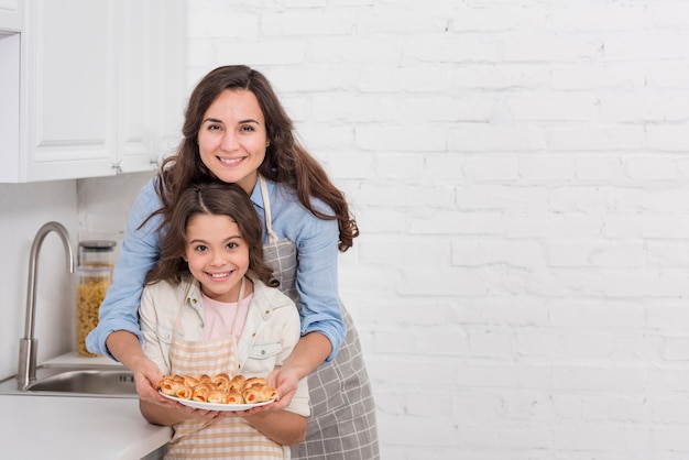 Foto gratuita madre e hija sosteniendo unos pasteles con espacio de copia