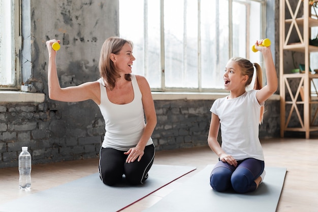 Madre e hija sosteniendo pesas sobre colchonetas de yoga
