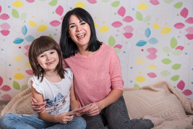 Madre e hija con tarjeta de felicitación sonriendo