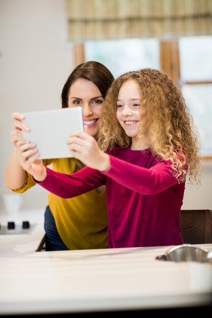 Madre e hija teniendo autofoto de tableta digital