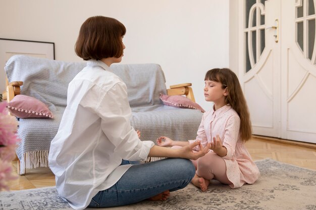 Madre e hija de tiro completo meditando juntos