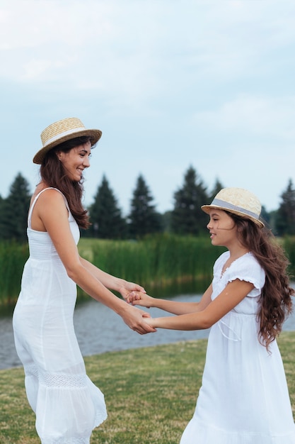 Madre e hija tomados de la mano por el lago