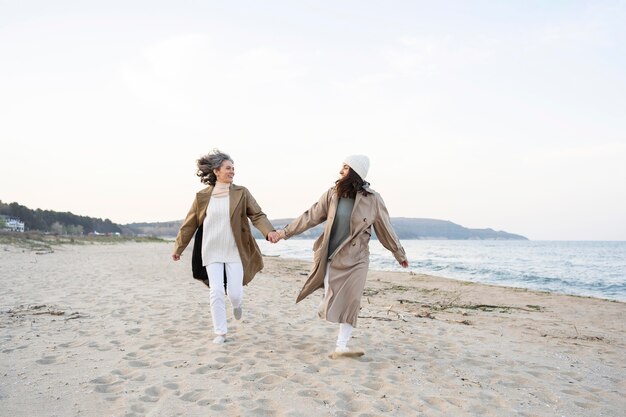 Madre e hija tomados de la mano mientras están juntos en la playa