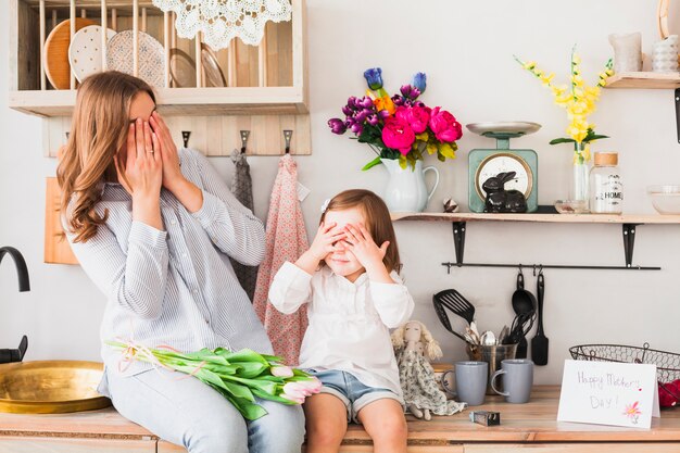 Madre e hija con tulipanes cubriendo los ojos