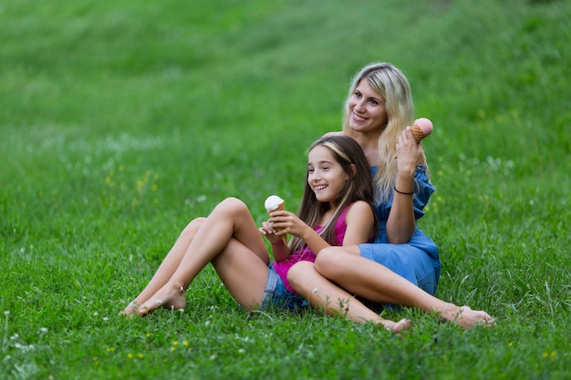 Madre e hija tumbada en la hierba con helado