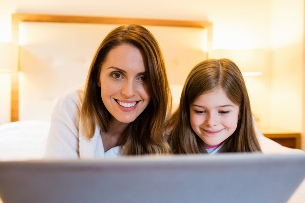 Madre e hija usando la computadora portátil en dormitorio