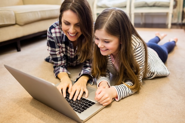 Foto gratuita madre e hija usando la computadora portátil en la sala de estar