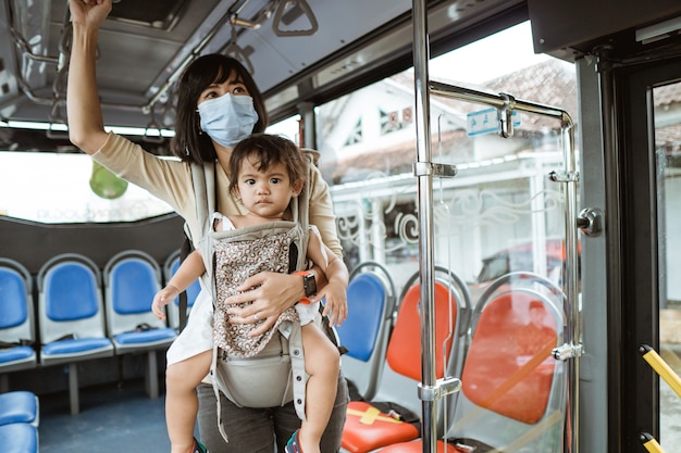 Madre e hija viajan en transporte público durante la pandemia con mascarilla