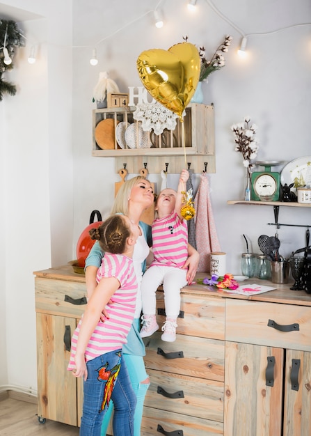 Foto gratuita madre e hijas con globo de corazón en cocina