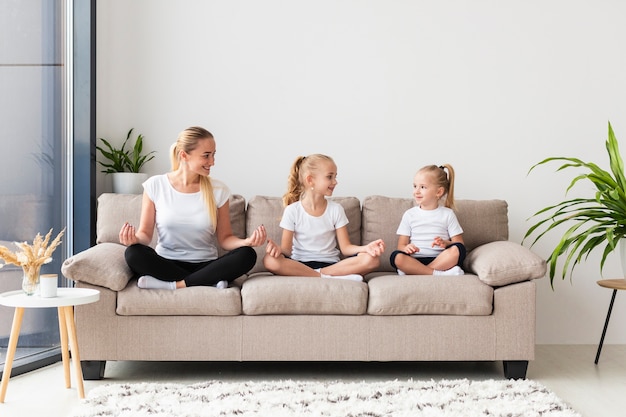 Madre e hijas haciendo ejercicio en casa en el sofá