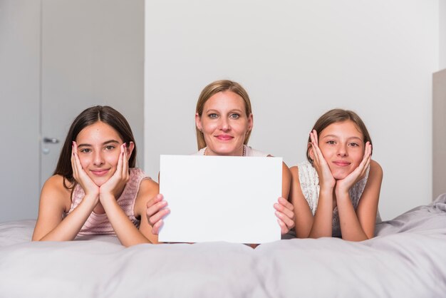 Foto gratuita madre e hijas con papel en blanco en la cama