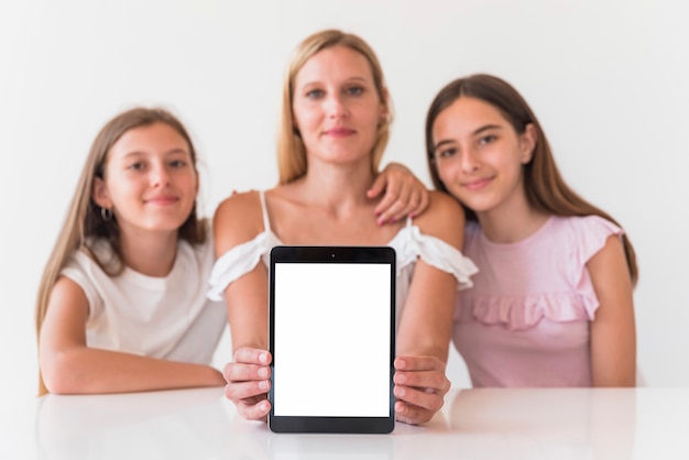 Madre e hijas sosteniendo tableta con pantalla en blanco