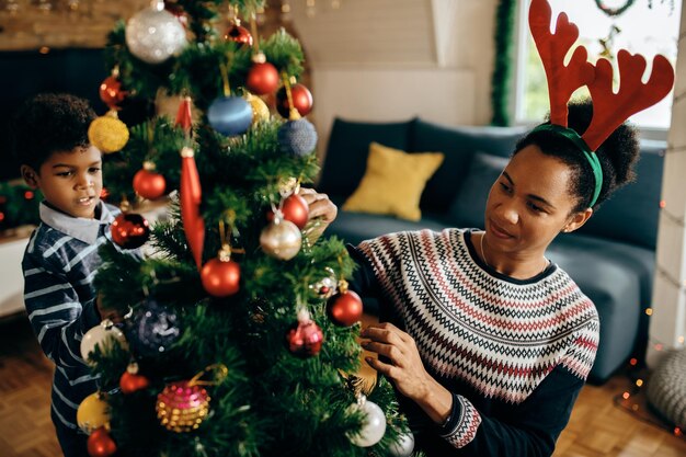 Madre e hijo afroamericanos decorando el árbol de Navidad en casa