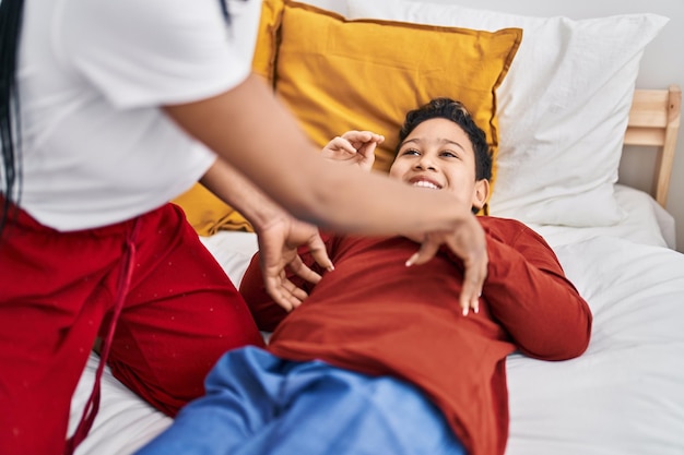 Foto gratuita madre e hijo afroamericanos haciendo cosquillas acostados en la cama en el dormitorio