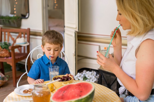 Madre e hijo bebiendo limonada fuera