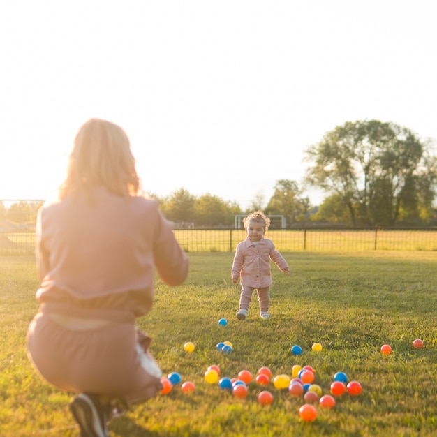 Madre e hijo jugando con pelotas de plástico en el parque