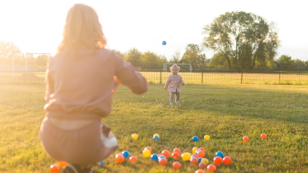 Madre e hijo jugando con pelotas de plástico tiro largo