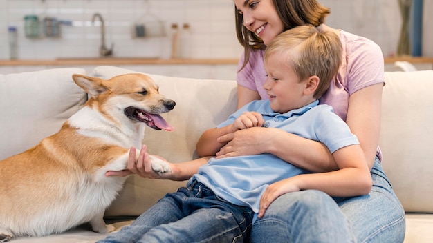 Madre e hijo jugando con perro corgi