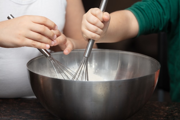 Foto gratuita madre e hijo mezclando algunos ingredientes para un pastel dentro de un tazón.