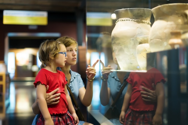 madre e hijo mirando ánforas viejas en el museo