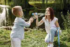 Foto gratuita madre e hijo pequeño descansando en el parque y posando para una foto. familia vistiendo ropa blanca y azul claro