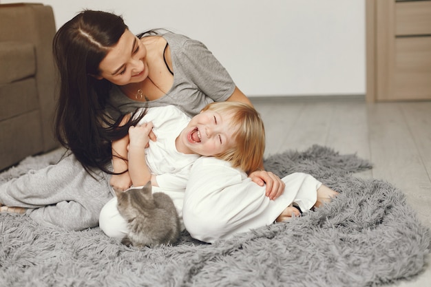 Madre e hijo pequeño divertido en casa con un gato