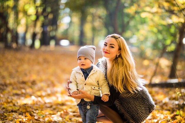 Madre e hijo pequeño en parque o bosque, al aire libre. Abrazar y divertirnos juntos en el parque de otoño