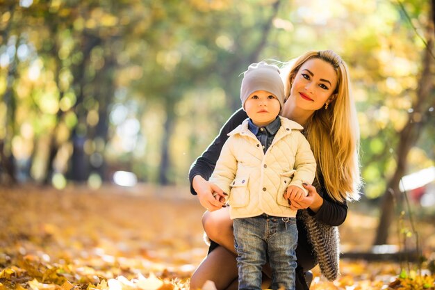 Madre e hijo pequeño en parque o bosque, al aire libre. Abrazar y divertirnos juntos en el parque de otoño