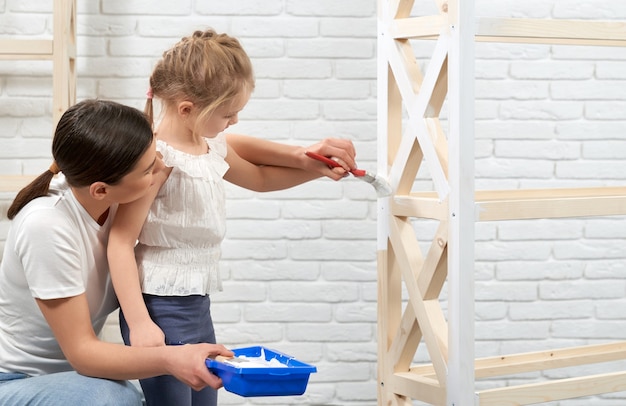 Foto gratuita madre e hijo pintando estante de madera.