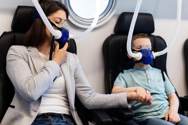 Madre e hijo respirando a través de máscaras de oxígeno y tomándose de la mano en una cámara hiperbárica en la clínica