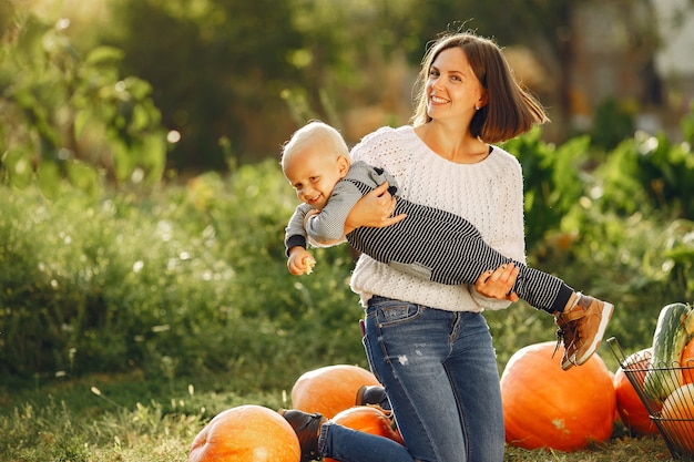 Madre e hijo sentados en un jardín cerca de muchas calabazas