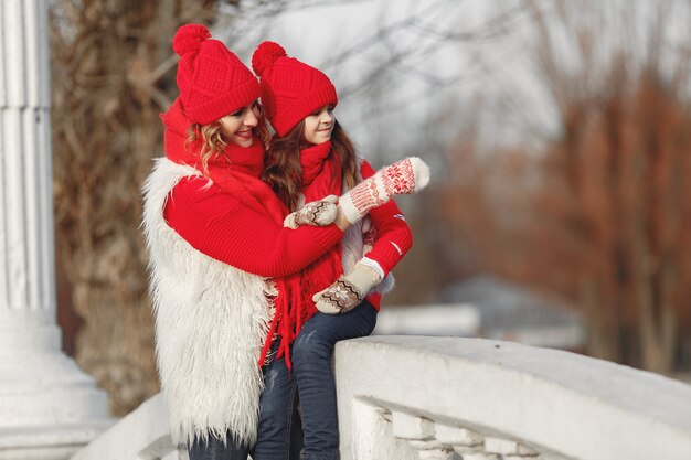 Madre e hijo con sombreros de invierno tejidos en vacaciones familiares de Navidad. Gorro y bufanda de lana hechos a mano para mamá y niño. Tejer para niños. Prendas de abrigo de punto. Mujer y niña en un parque.