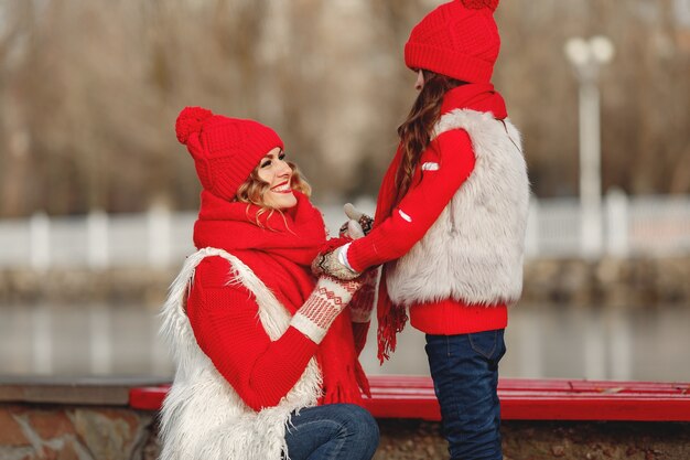 Madre e hijo con sombreros de invierno tejidos en vacaciones familiares de Navidad. Gorro y bufanda de lana hechos a mano para mamá y niño. Tejer para niños. Prendas de abrigo de punto. Mujer y niña en un parque.