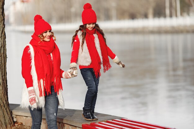 Madre e hijo con sombreros de invierno tejidos en vacaciones familiares de Navidad. Gorro y bufanda de lana hechos a mano para mamá y niño. Tejer para niños. Prendas de abrigo de punto. Mujer y niña en un parque.