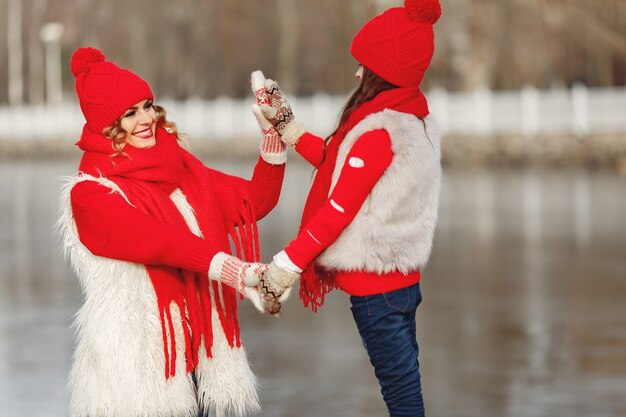 Madre e hijo con sombreros de invierno tejidos en vacaciones familiares de Navidad. Gorro y bufanda de lana hechos a mano para mamá y niño. Tejer para niños. Prendas de abrigo de punto. Mujer y niña en un parque.