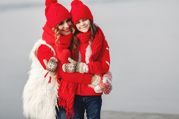 Madre e hijo con sombreros de invierno tejidos en vacaciones familiares de Navidad. Gorro y bufanda de lana hechos a mano para mamá y niño. Tejer para niños. Prendas de abrigo de punto. Mujer y niña en un parque.