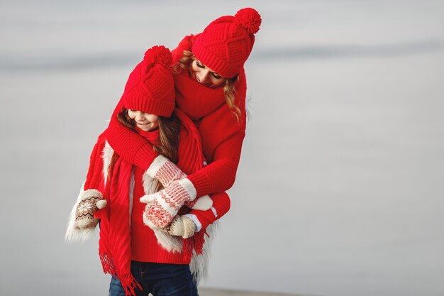 Madre e hijo con sombreros de invierno tejidos en vacaciones familiares de Navidad. Gorro y bufanda de lana hechos a mano para mamá y niño. Tejer para niños. Prendas de abrigo de punto. Mujer y niña en un parque.