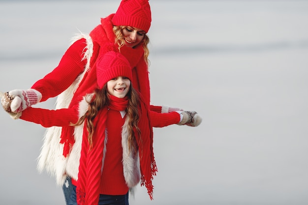 Madre e hijo con sombreros de invierno tejidos en vacaciones familiares de Navidad. Gorro y bufanda de lana hechos a mano para mamá y niño. Tejer para niños. Prendas de abrigo de punto. Mujer y niña en un parque.