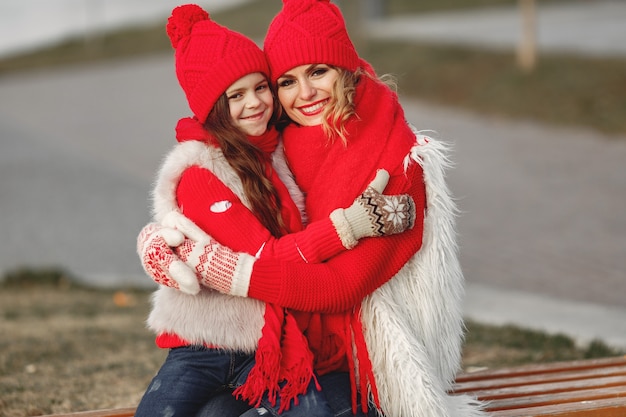 Madre e hijo con sombreros de invierno tejidos en vacaciones familiares de Navidad. Gorro y bufanda de lana hechos a mano para mamá y niño. Tejer para niños. Prendas de abrigo de punto. Mujer y niña en un parque.