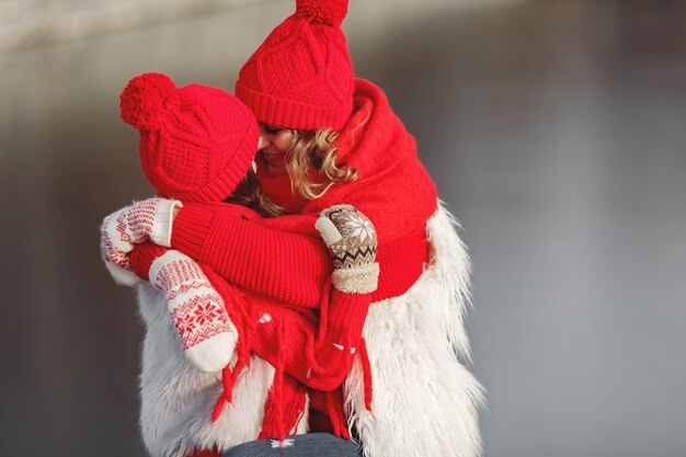 Madre e hijo con sombreros de invierno tejidos en vacaciones familiares de Navidad. Gorro y bufanda de lana hechos a mano para mamá y niño. Tejer para niños. Prendas de abrigo de punto. Mujer y niña en un parque.