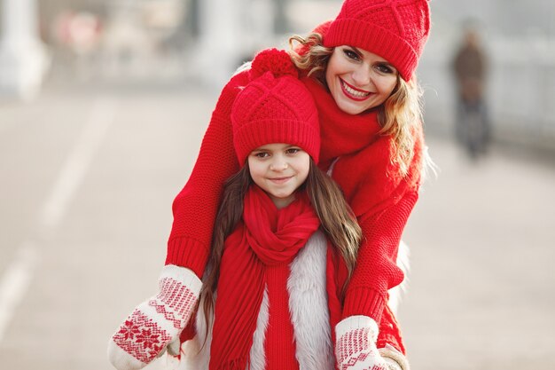 Madre e hijo con sombreros de invierno tejidos en vacaciones familiares de Navidad. Gorro y bufanda de lana hechos a mano para mamá y niño. Tejer para niños. Prendas de abrigo de punto. Mujer y niña en un parque.