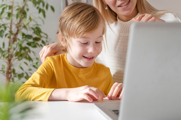 Madre e hijo sonrientes usando laptop en casa