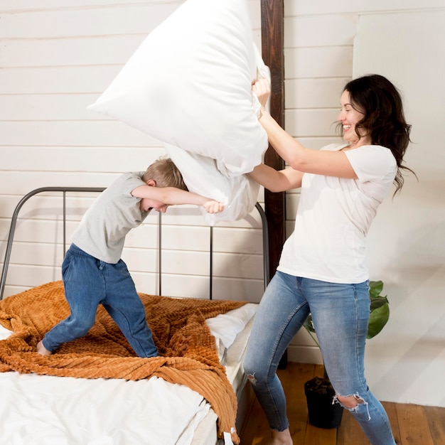 Foto gratuita madre e hijo teniendo pelea de almohadas