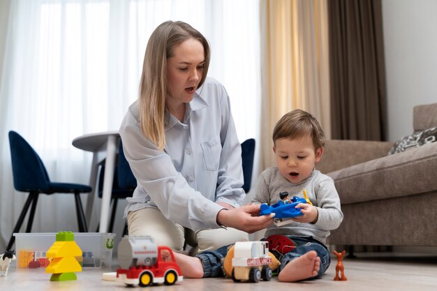 Foto gratuita madre e hijo de tiro completo con buenos juguetes.