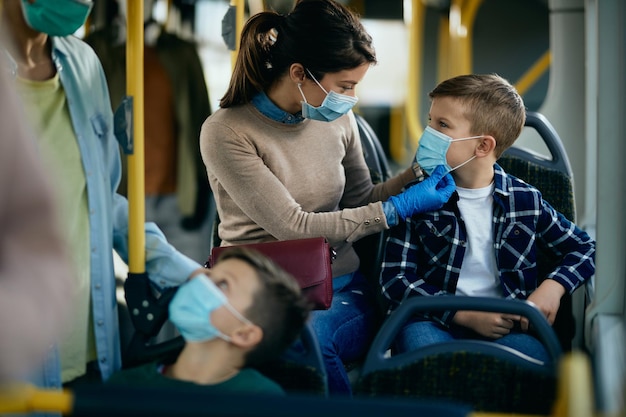 Foto gratuita madre e hijo viajando en autobús con medidas de precaución durante la pandemia del coronavirus