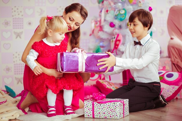 Madre e hijos abriendo regalos de navidad